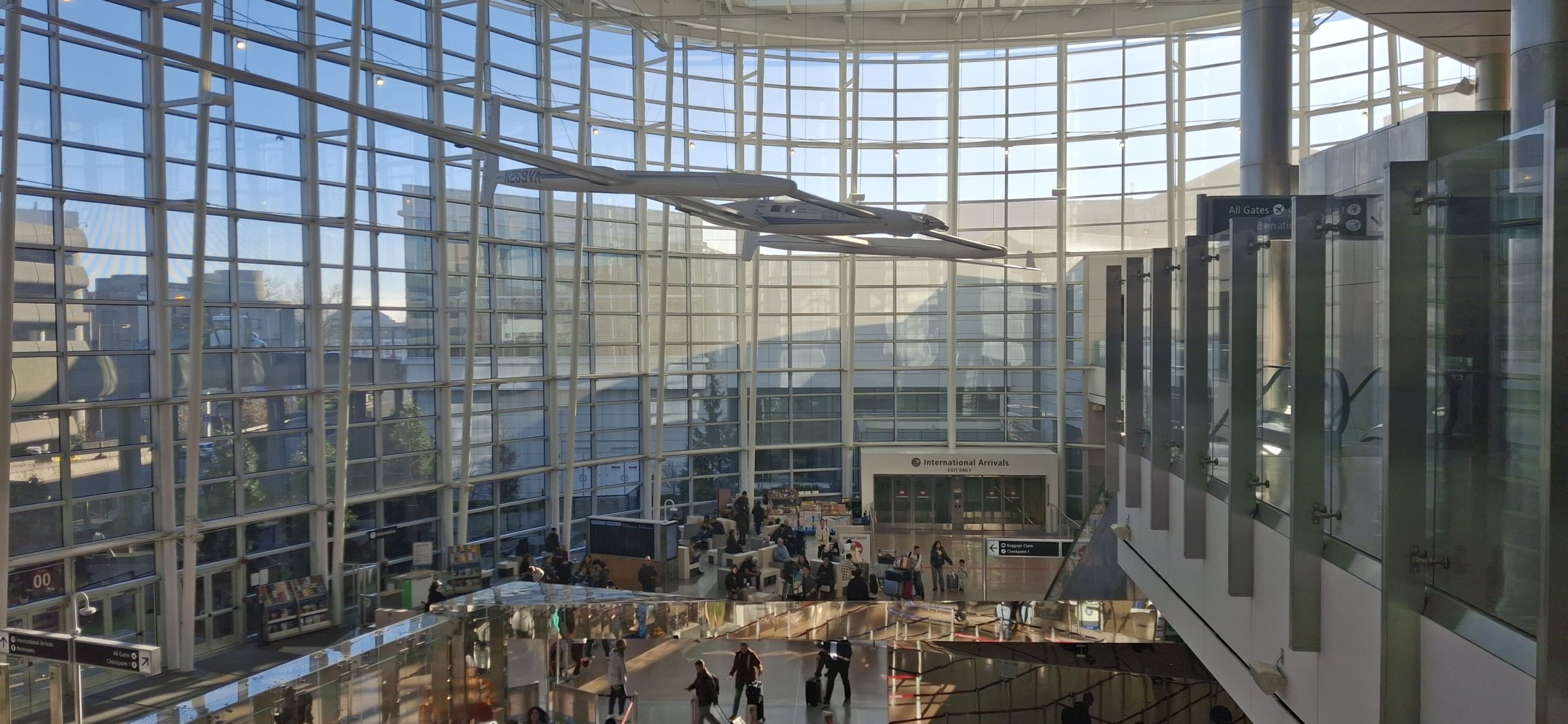 The glass-walled Central Terminal hall at Seattle–Tacoma International Airport, with the International Arrivals sign