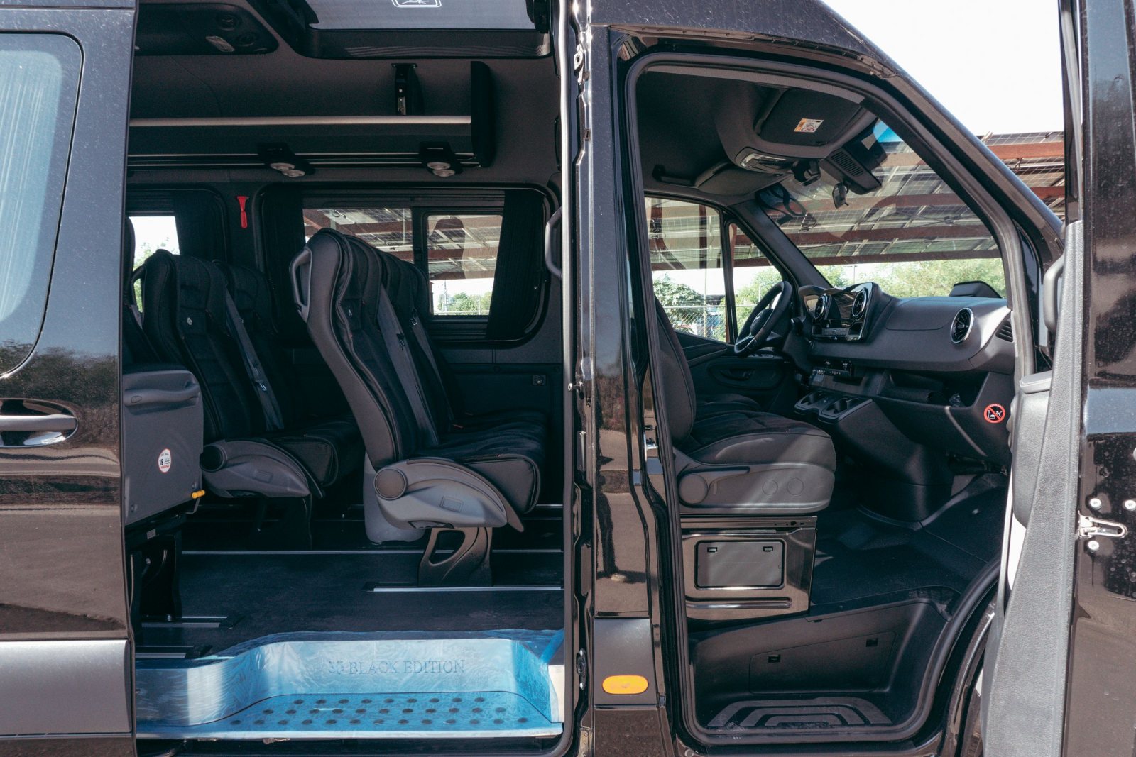 Black Mercedes-Benz Sprinter van with its doors open, showing black leather passenger seats