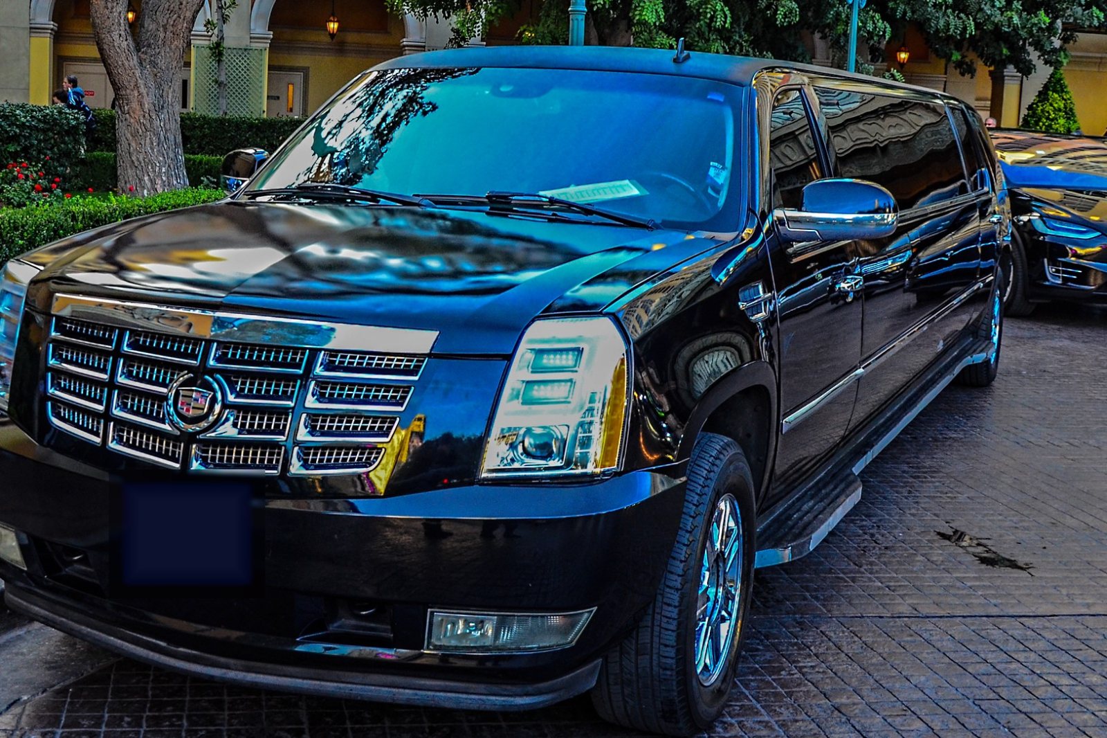 Black Cadillac Escalade stretch limousine parked at a hotel entrance