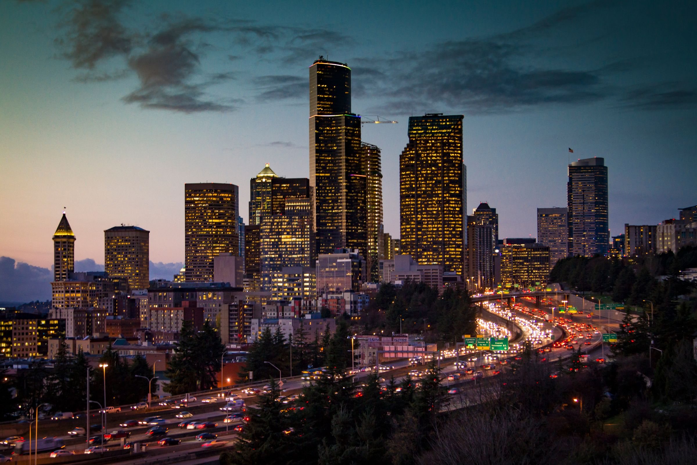 Downtown Seattle skyline at dusk, with the Smith Tower and evening traffic on I-5 below