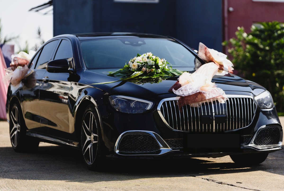 Black Mercedes-Maybach sedan decorated with white flowers and ribbons for a wedding
