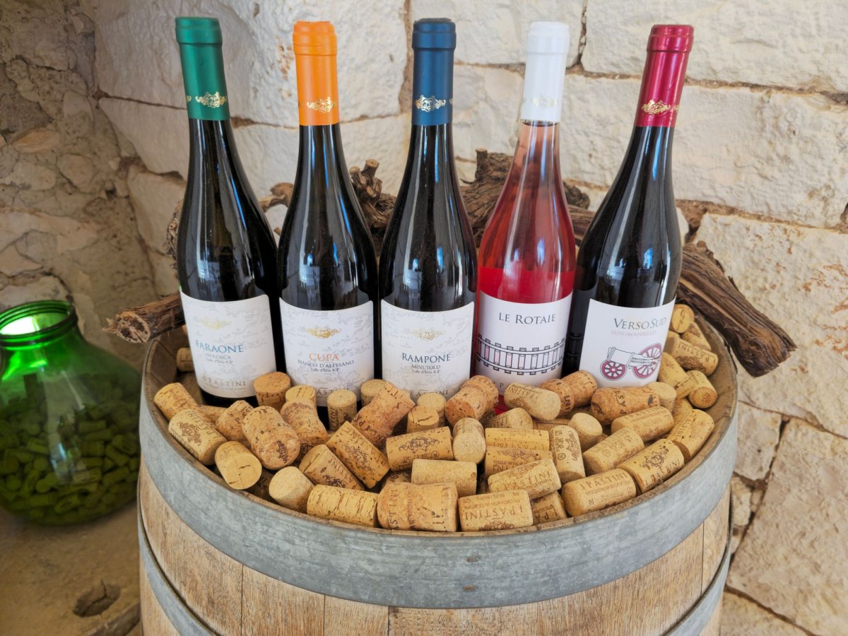 Five wine bottles standing in a barrel filled with corks